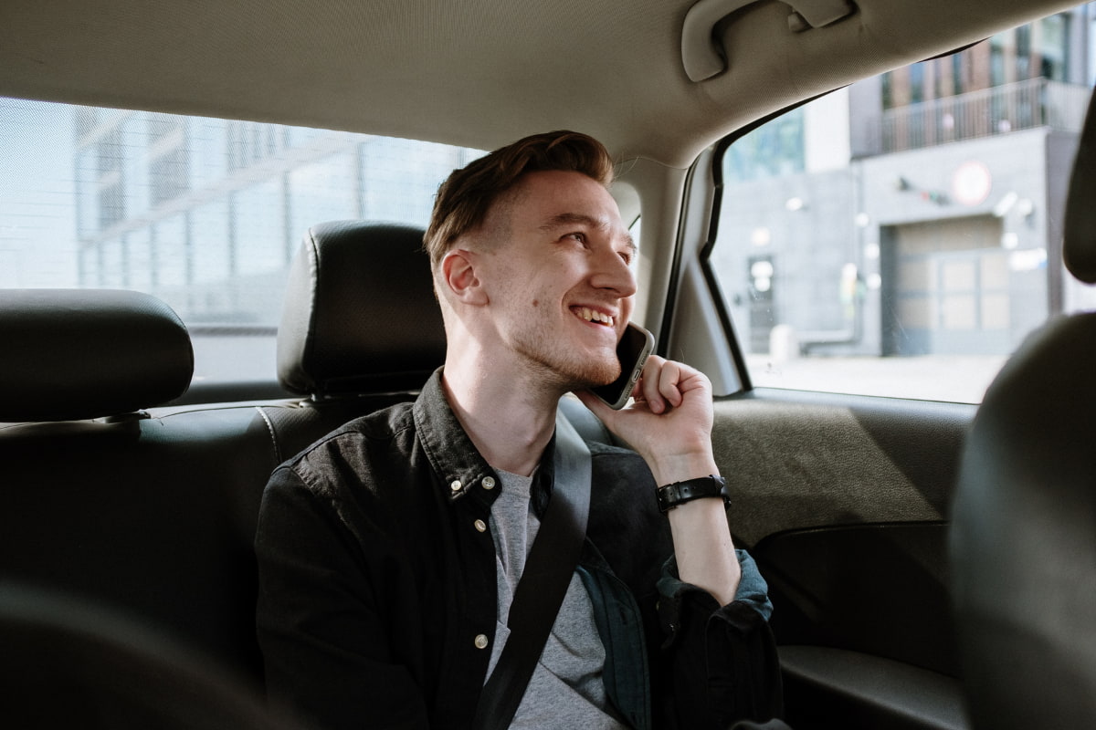 Man talking on the phone sitting on the back seat of a car