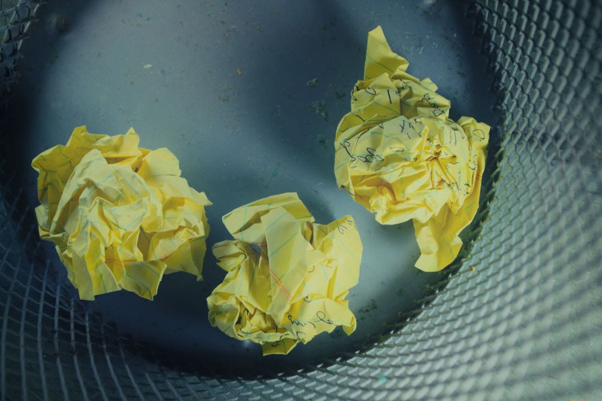 Three crumpled pieces of paper inside a garbage can