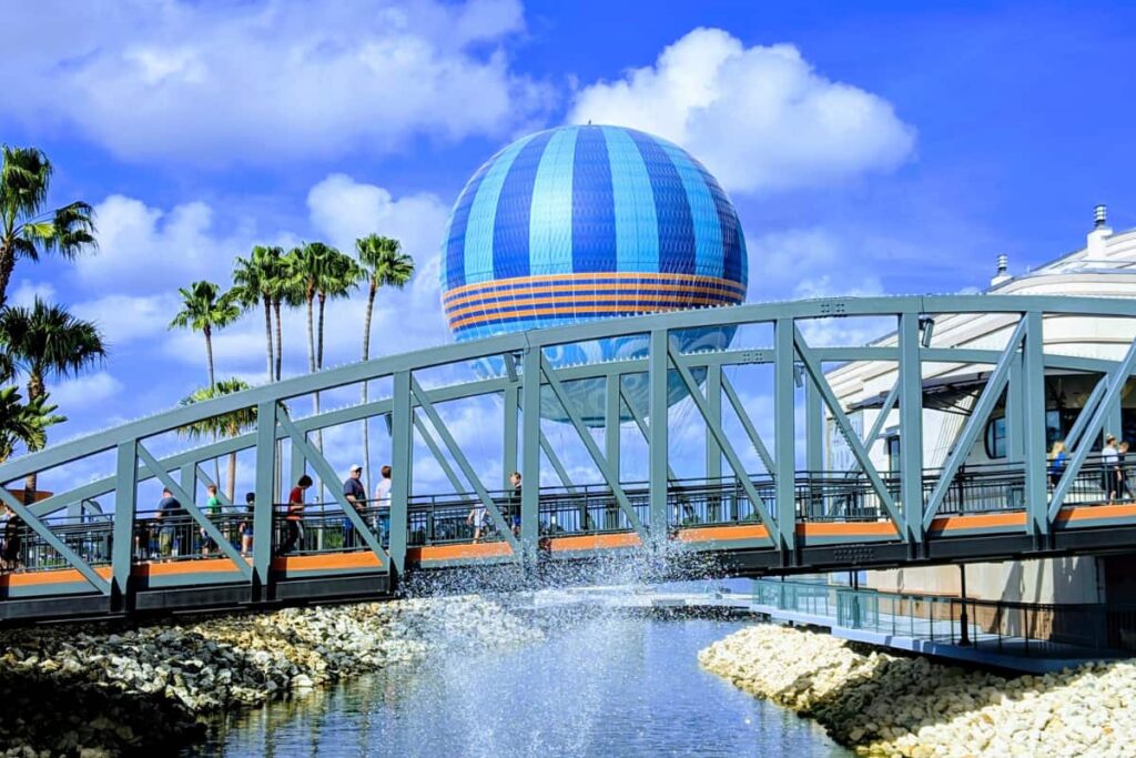 People walking on a bridge with a huge balloon in the background at Disney Springs