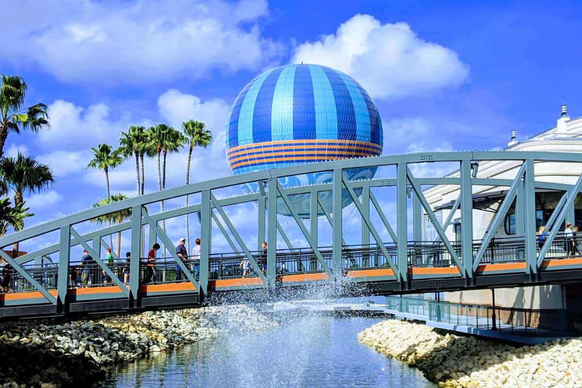 People walking on a bridge with a huge balloon in the background at Disney Springs