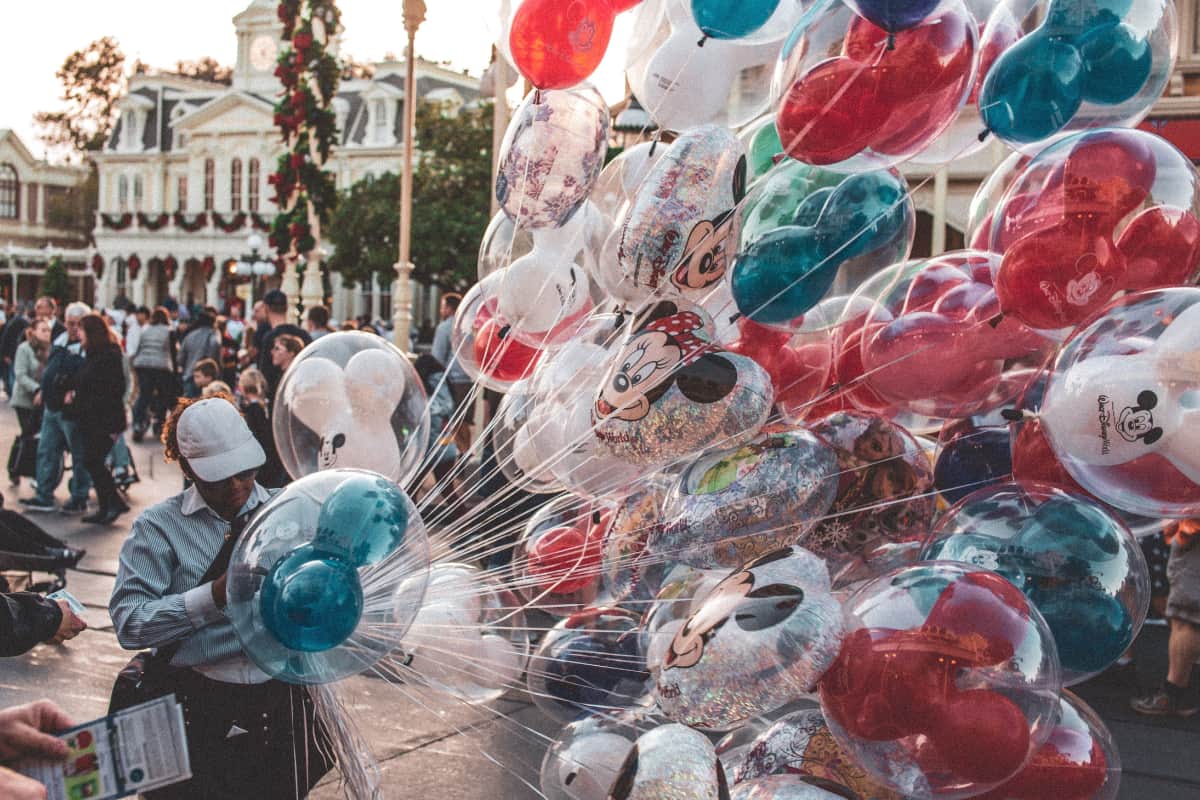 Person displaying assorted helium balloons with Disney designs