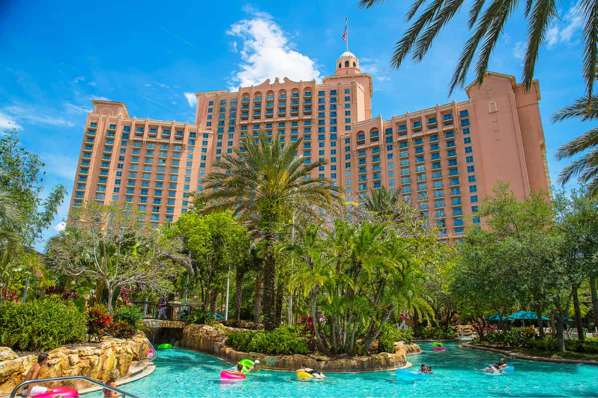 Palm trees surrounding a pool with a huge hotel building in the background