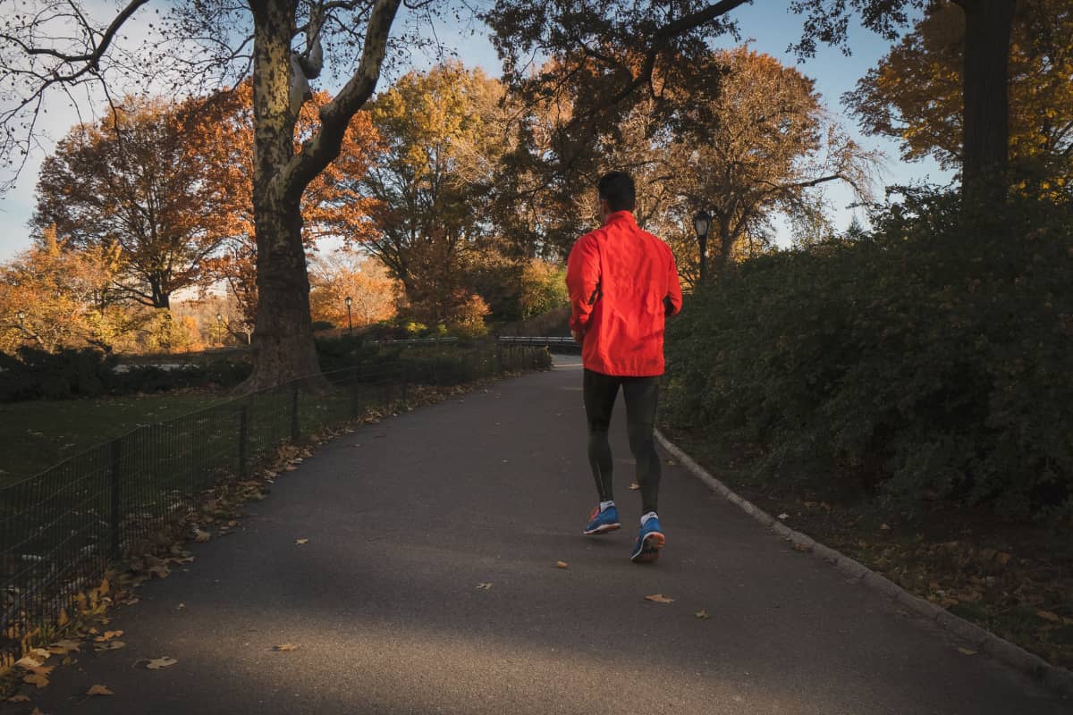 Person wearing an orange jacket going on a light jog in the park
