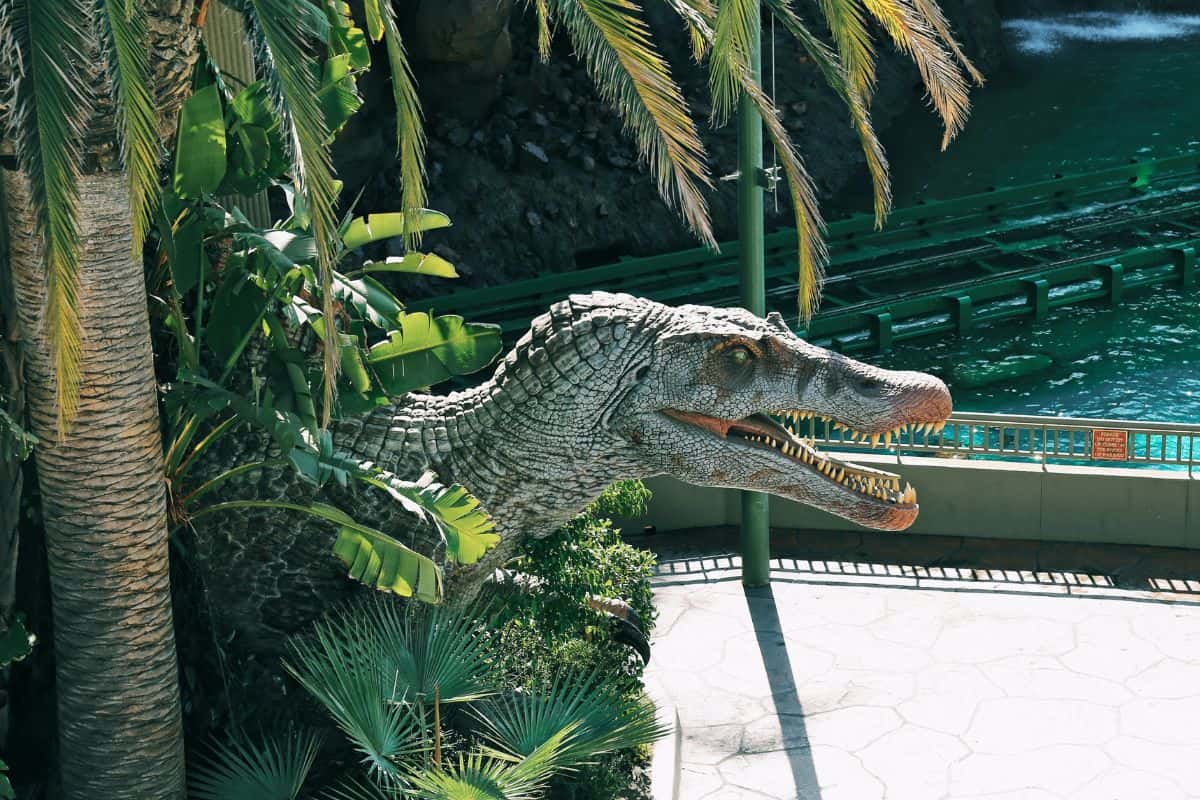 Dinosaur animatronic peeking through some plants at trees at the Jurassic Park in Universal Orlando