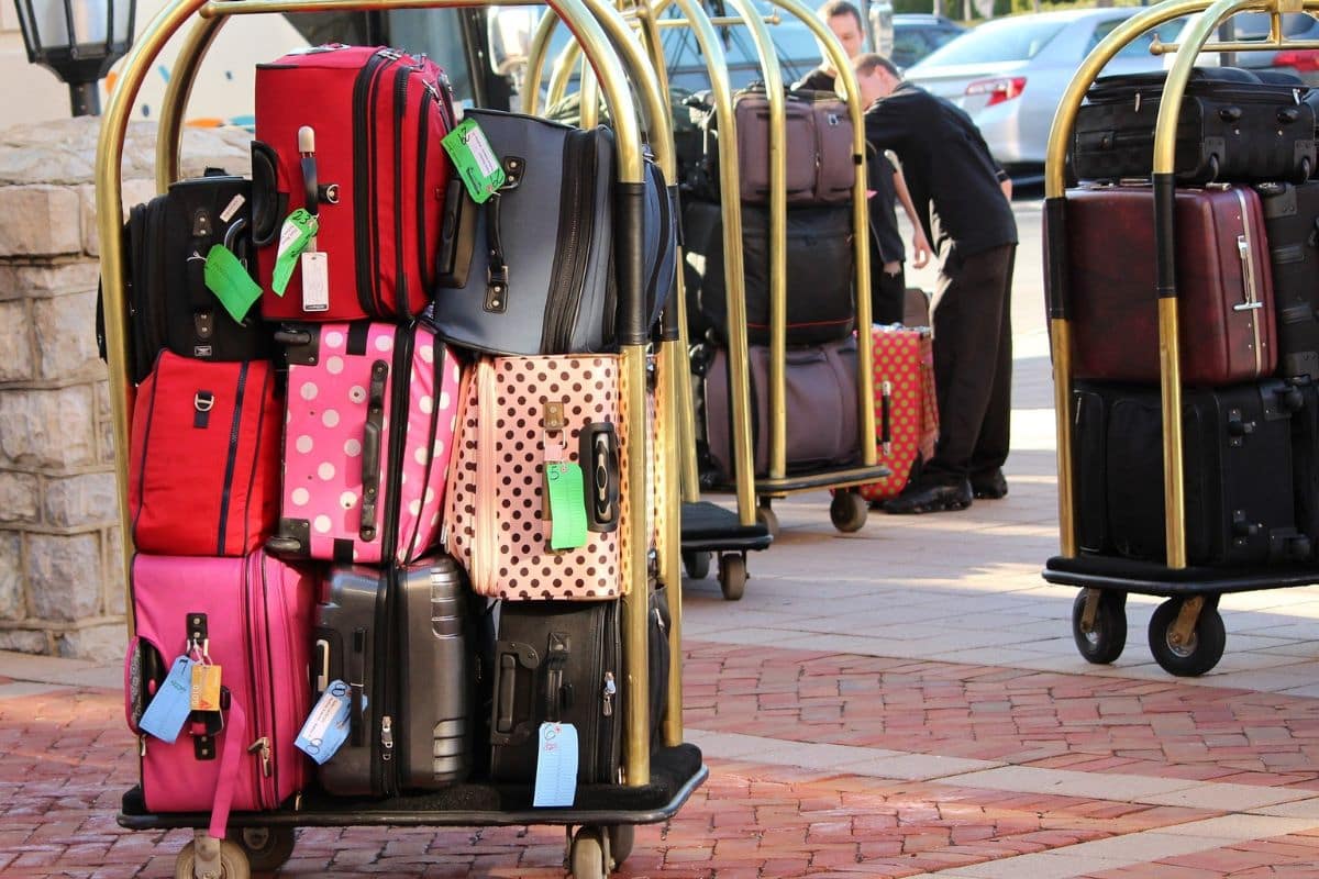 Multiple different colored suitcases stacked on a luggage trolley