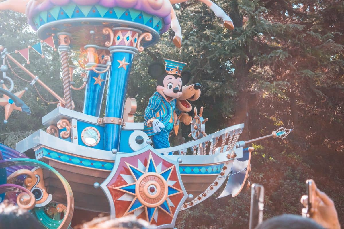 Two people in Mickey Mouse and Pluto costumes riding a float in Disneyland