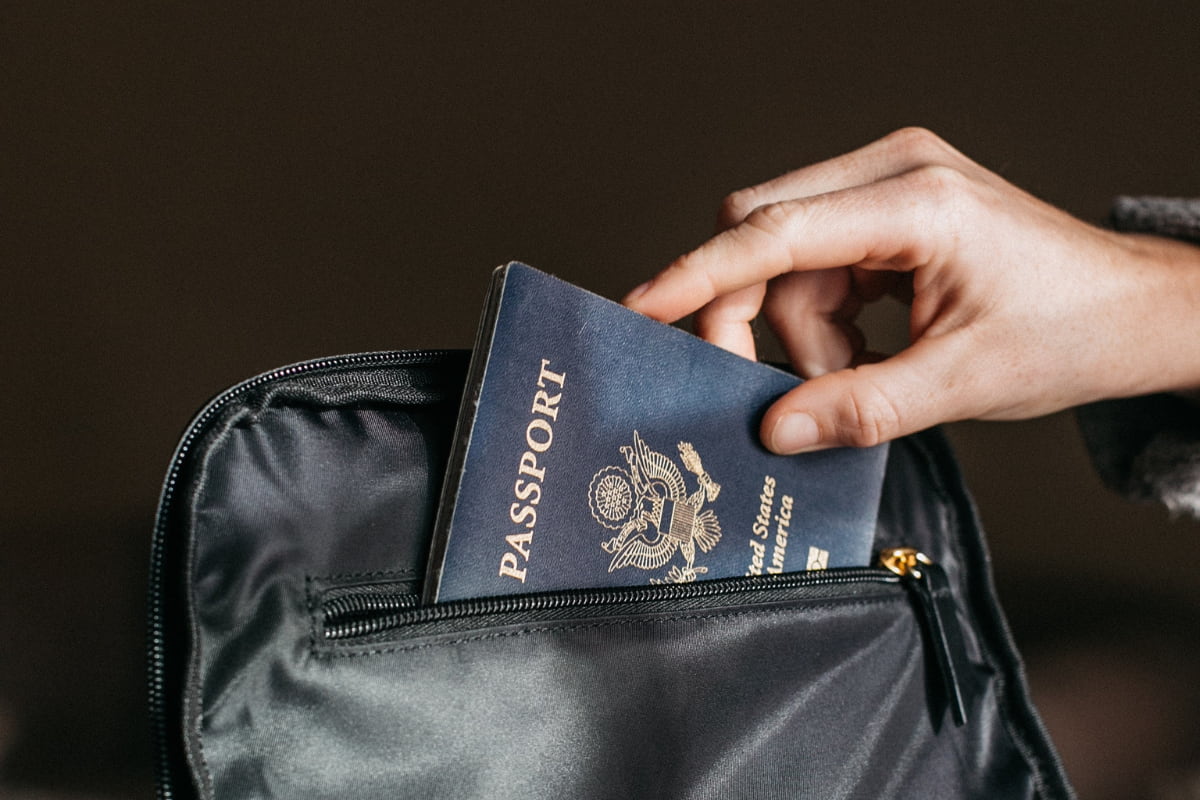Close up of a person's hand putting a passport inside of a bag