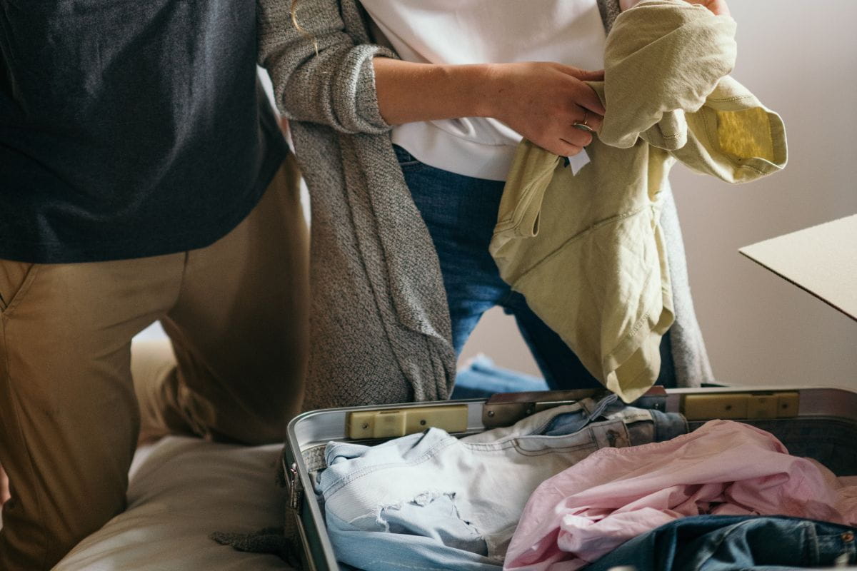Two people packing clothes into a suitcase