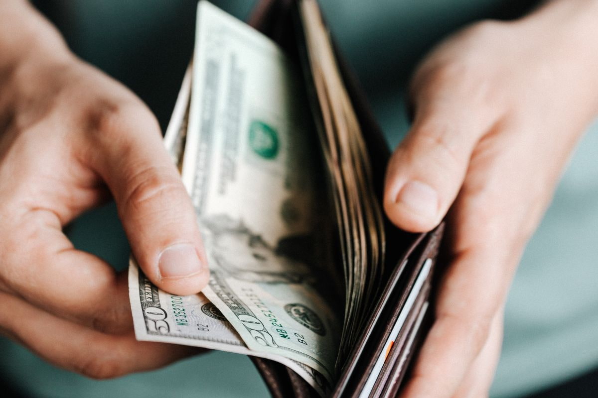 Close up of a person's hands holding a wallet and taking out cash