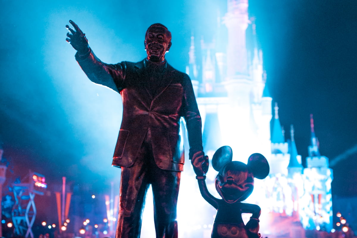 Statue of Walt Disney and Mickey Mouse in front of Cinderella's Castle at night