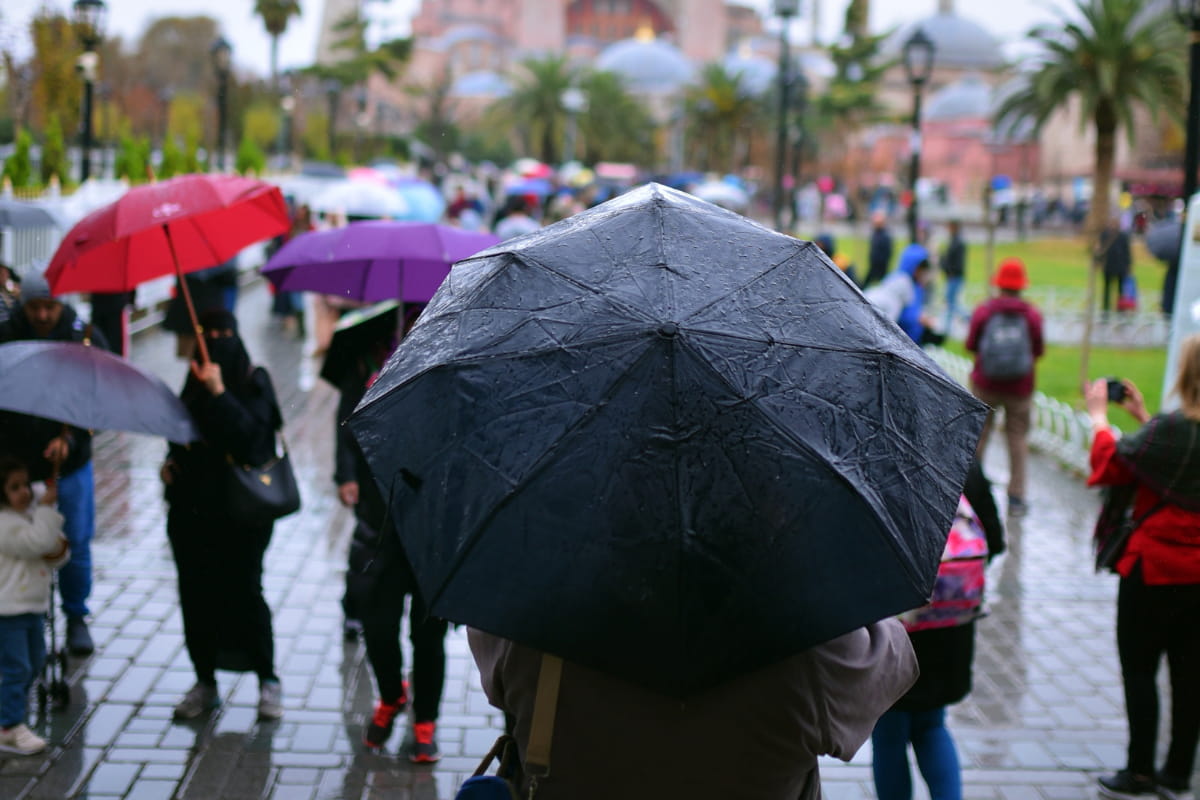 Person holding an umbrella in front of a crowd while it's raining