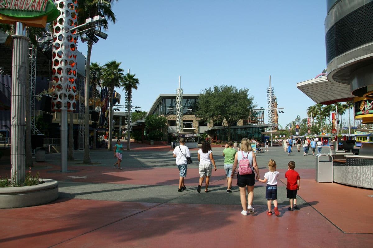 Two children accompanied by an adult walking at a theme park