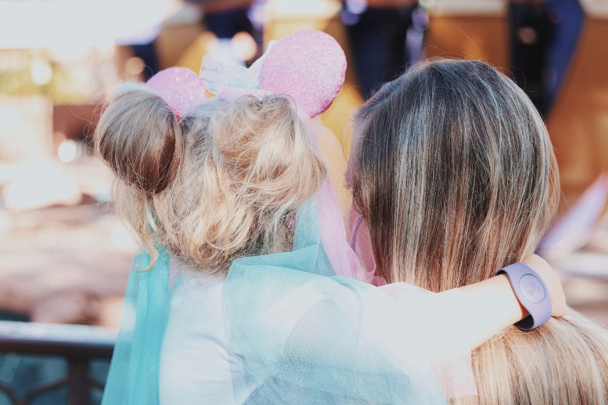 Woman carrying a child wearing pink Minnie Mouse ears