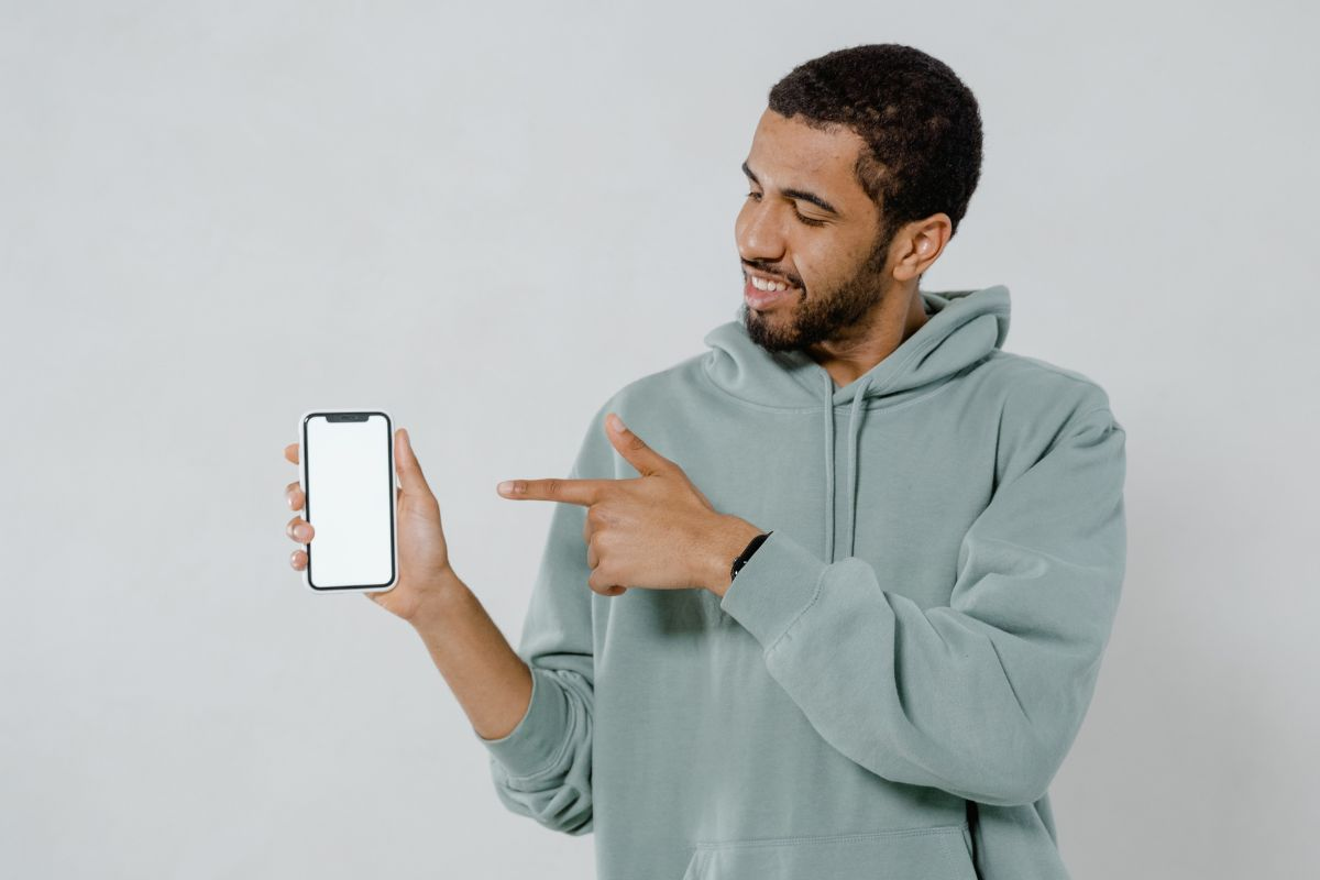 Man in a hoodie showing his phone screen
