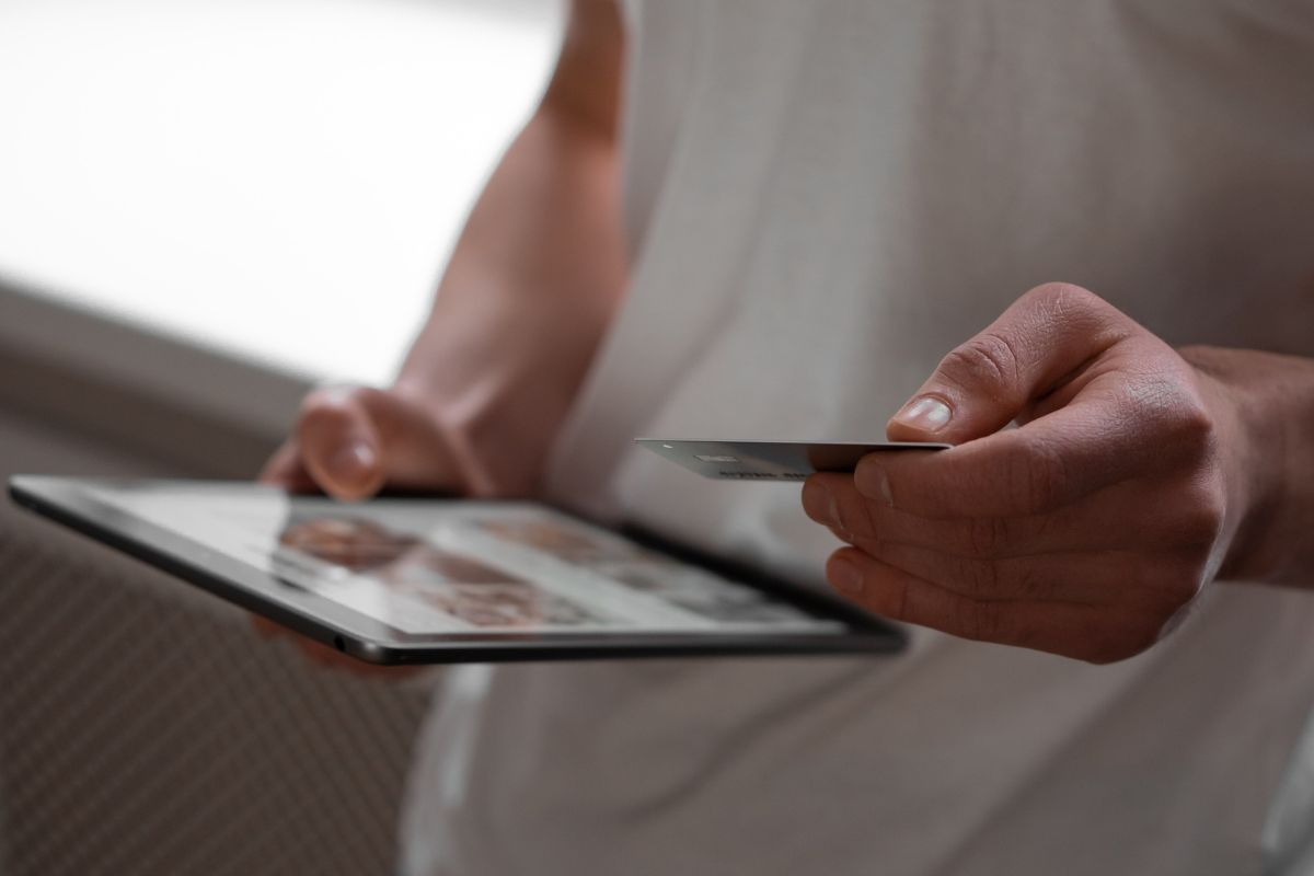 Person holding a card while using a tablet