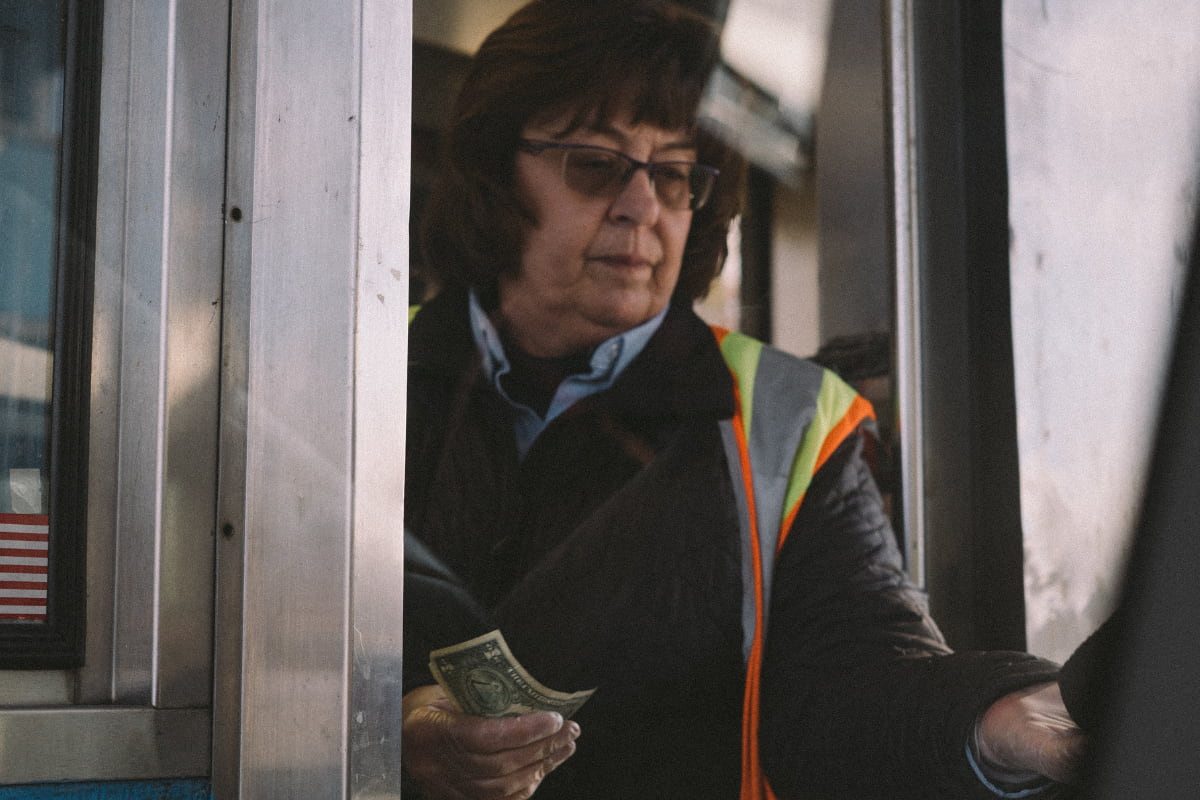Woman inside a toll booth in the middle of a transaction
