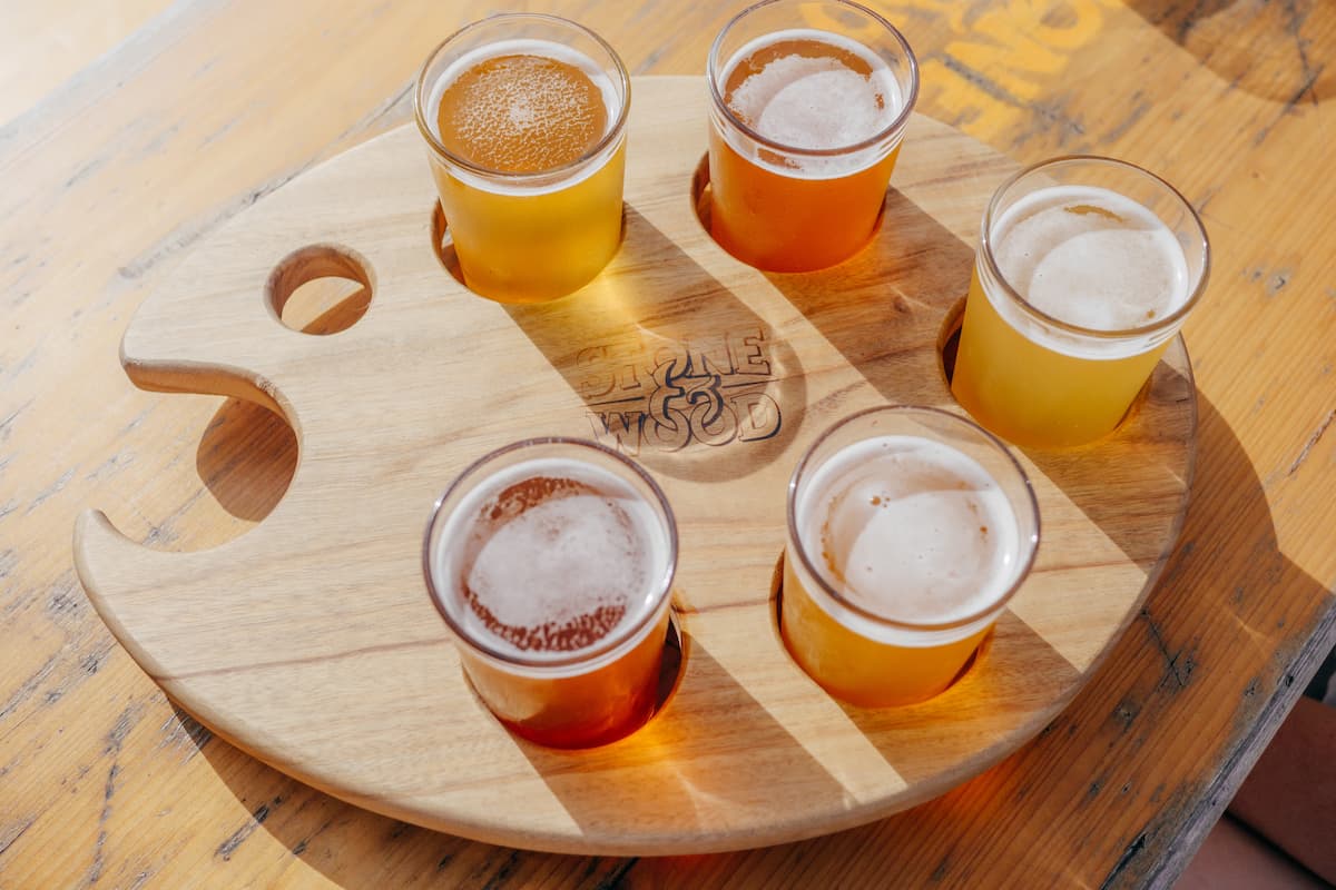 Five glasses of beer on a brown wooden tray. 