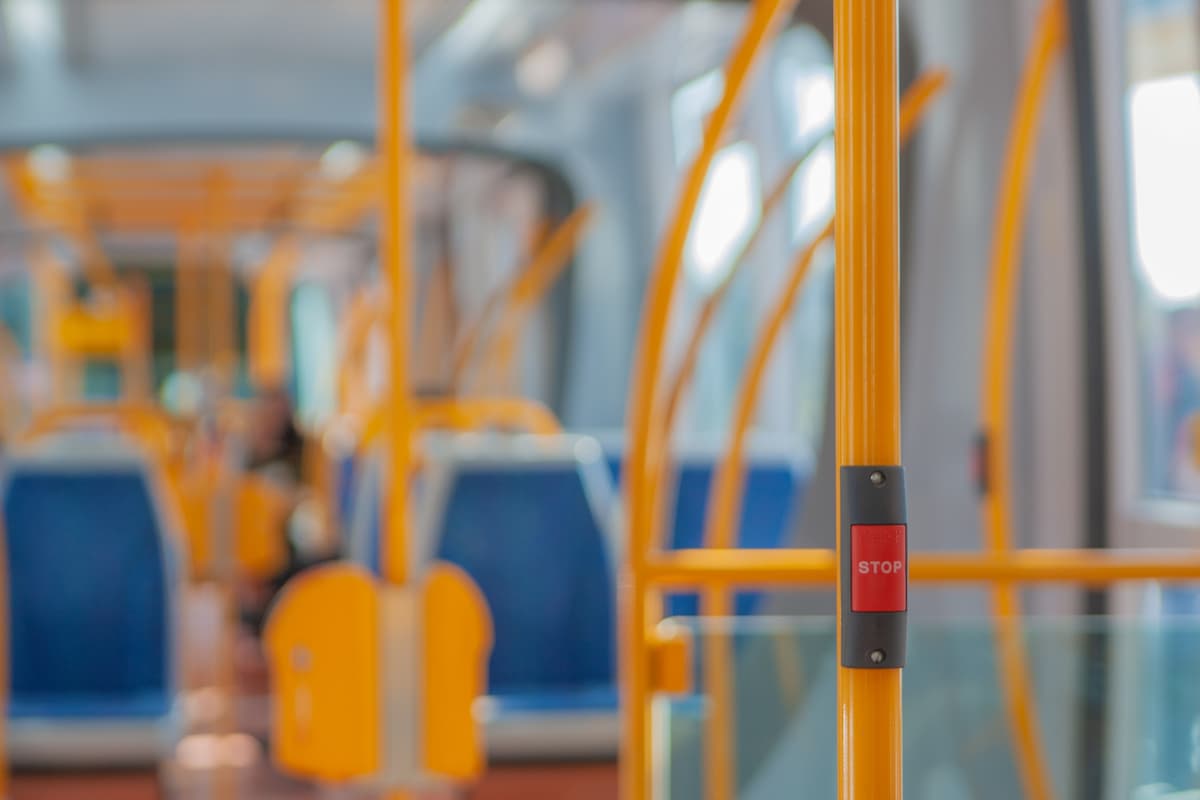 A blurred photo of the interior of a bus focusing on the stop button.