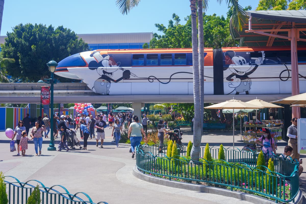 Photo of Walt Disney Monorail System and people walking around the theme park.  