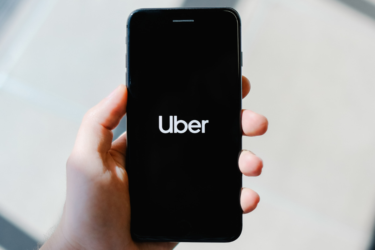 Close up of a person's hand holding a smartphone with the Uber logo on the screen