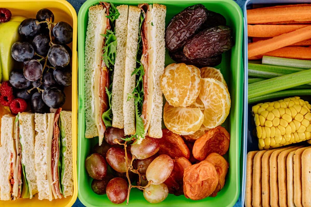 Sandwiches, vegetables, and fruits inside lunchboxes