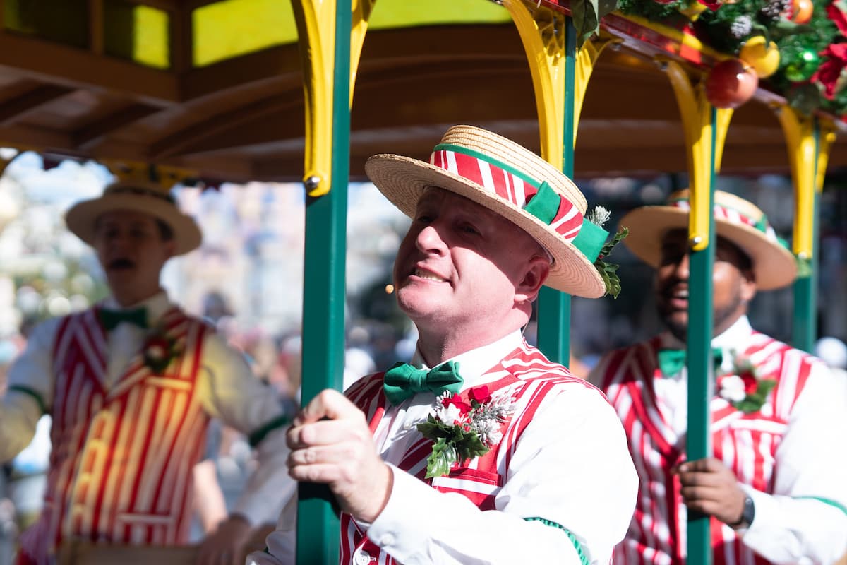 Three men wearing hats while riding a float during Disney World parades.