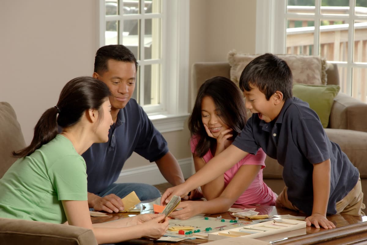 A family of four is playing a board game in the living room.
