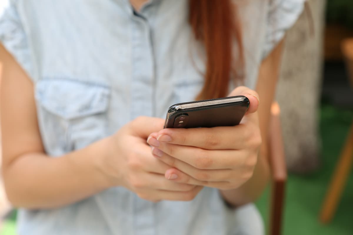 Cropped photo of a woman using a black smartphone. 