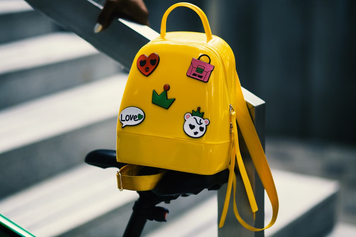 Photo of a yellow backpack with five assorted stickers.