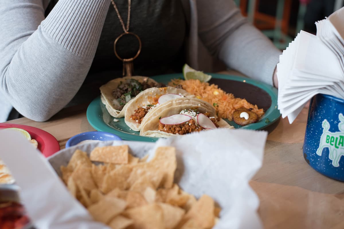 Woman sitting in front of tacos on a plate.