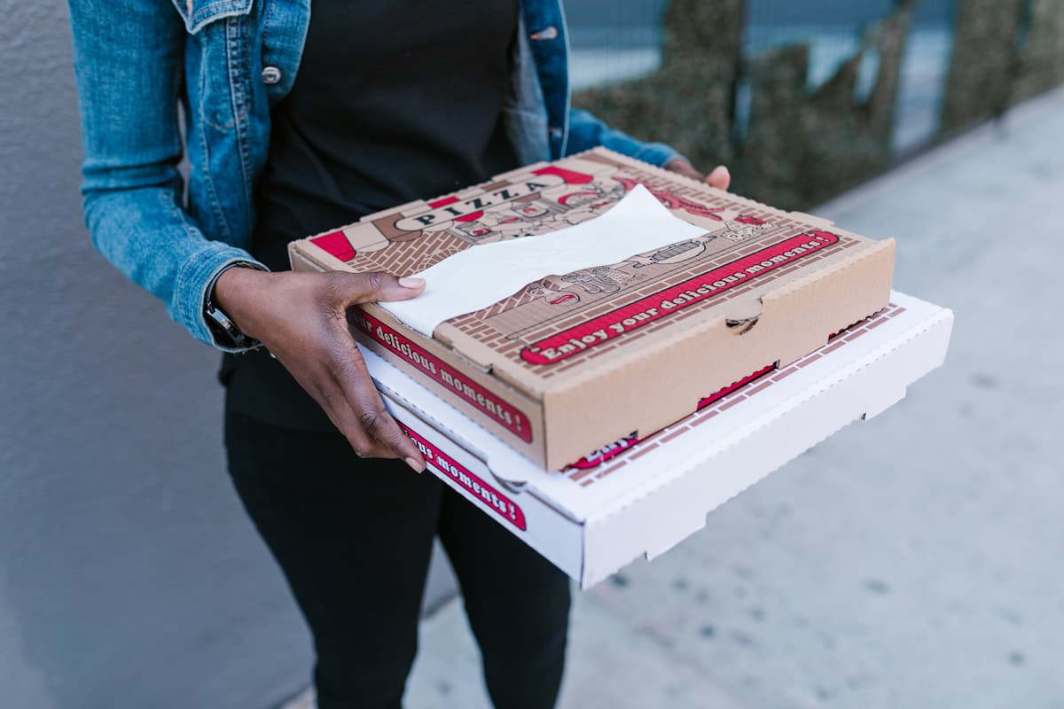 Cropped photo of a woman holding two boxes of pizza.